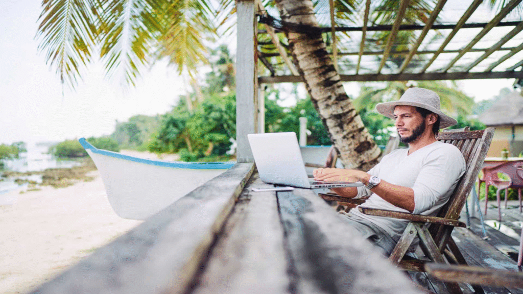 Travel entrepreneur researching Startup Funding in South Africa on a laptop at a tropical beachside lodge.